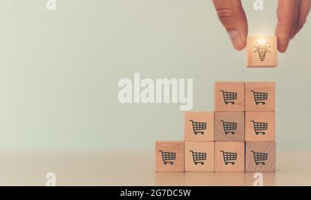 Business growth strategy and key success factor concept to increase sales volume, man holds cube with light icon symbol on many shopping cart icon; co Stock Photo