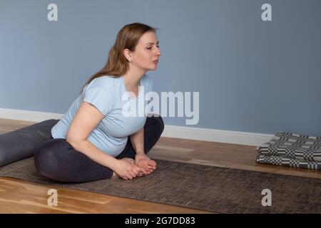 Pregnant woman doing morning yoga sitting in Baddha Konasana or Bound Angle Stock Photo