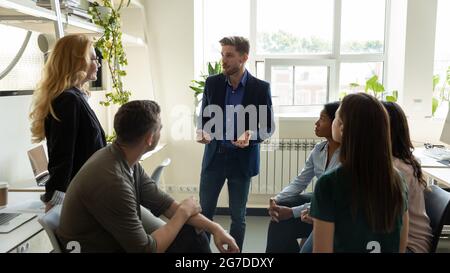 Confident millennial business leader, presenter speaking before team Stock Photo