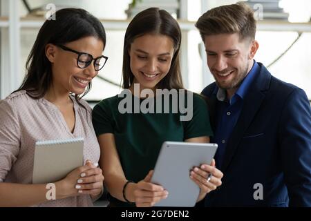 Happy satisfied diverse young business team of employees using tablet Stock Photo