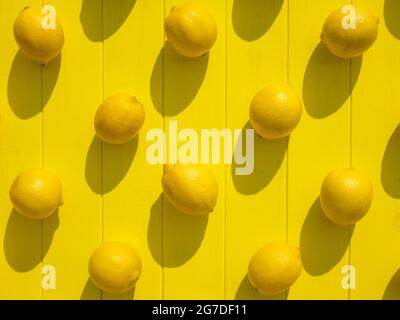 Ripe lemons on the yellow wooden surface, top view. Vibrant background Stock Photo