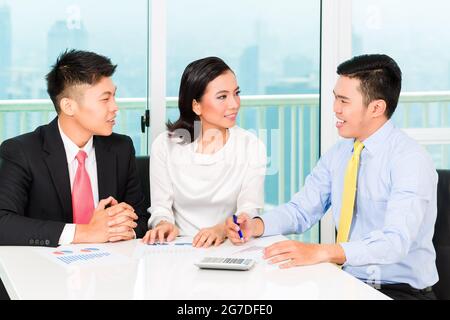 Asian banker selling insurance to couple in office Stock Photo