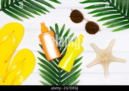Summer holiday concept. Sunscreen spray, sunglasses, flip flops, starfish with tropical palm leaves. Summertime flat lay composition Stock Photo
