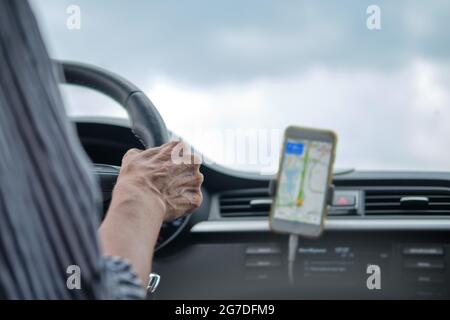 A woman drives a car using the navigator in a mobile phone Stock Photo