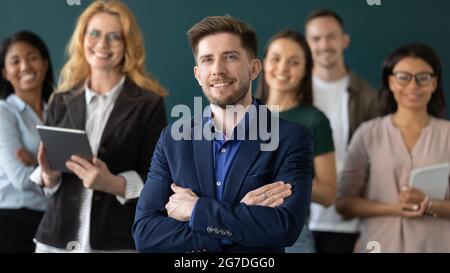 Happy male business leader posing with team in blurred background Stock Photo