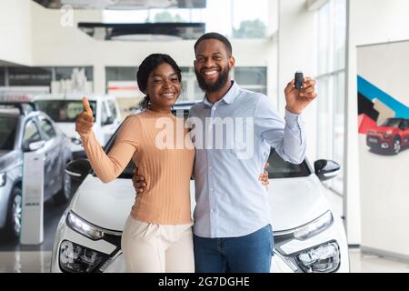 Happy Black Couple Holding Keys From New Car And Showing Thumb Up Stock Photo