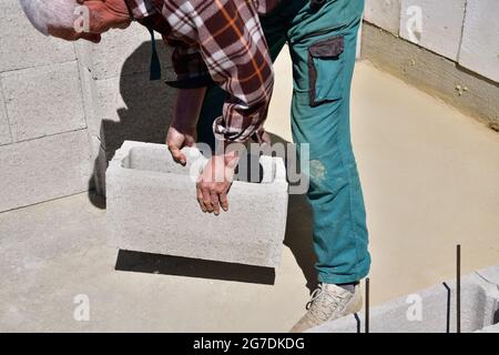 The mason places and prefabricated blocks into the wall at home on the construction site Stock Photo
