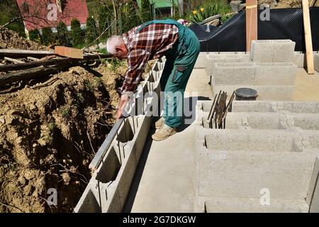 The mason places and prefabricated blocks into the wall at home on the construction site Stock Photo