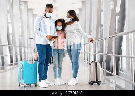 Masked black family travelling, looking at documents in airport Stock Photo