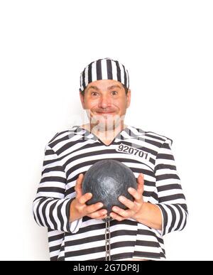 prisoner in a striped jacket and cap chained with an iron core with shackles in full face on a white background Stock Photo