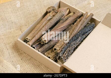 Full Cardboard Pet Treat Box on burlap fabric. Dried dog goodies. Tasty Beef Tripe Sticks. Bovine stomach. Selective focus Stock Photo