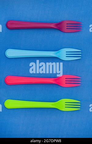 brightly colored plastic forks on colorful background with copy space Stock Photo