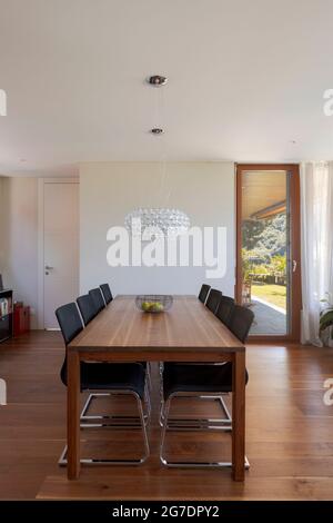 Front view dining room with wood table, leather chairs and dark hardwood floors. Stylish modern home. Nobody inside Stock Photo