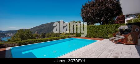 Large modern pool overlooking the lake and valley, nestled in the mountains of Switzerland. Sunny day, perfect for a vacation. Nobody inside Stock Photo