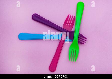 brightly colored plastic forks on colorful background with copy space Stock Photo