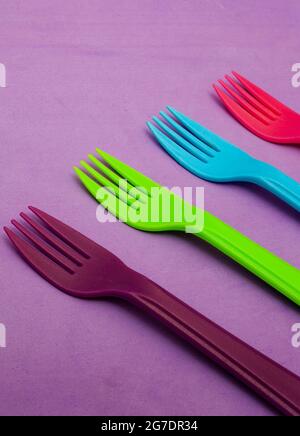 brightly colored plastic forks on colorful background with copy space Stock Photo