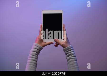 Close-up of hands with tablet and blank black screen on blank purple background. Stock Photo