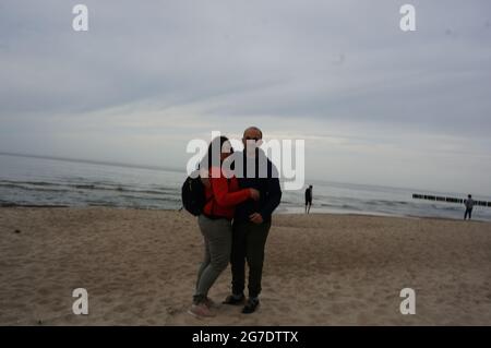 TRZESACZ, POLAND - Jun 04, 2021: A man and woman standing on sand at a beach in the evening in Trzesacz, Poland Stock Photo