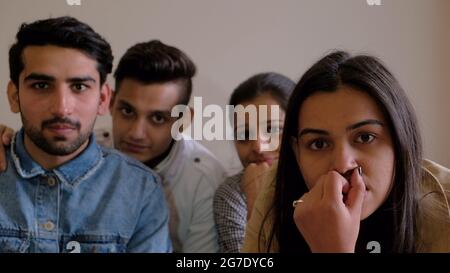 Group of young Indian males and females seriously looking at something Stock Photo