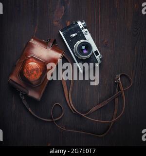 Vintage photo camera and holster on wooden background. Top view. Flat lay. Stock Photo