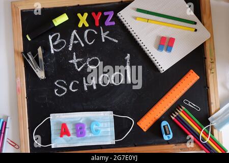 the inscription back to school on the blackboard among the school supplies Stock Photo