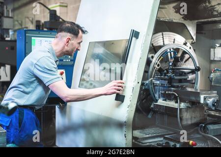 Worker man operating a CNC lathe in factory Stock Photo