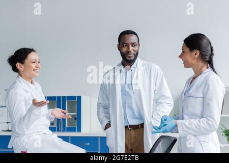 Smiling multiethnic doctors in white coats talking in clinic Stock Photo