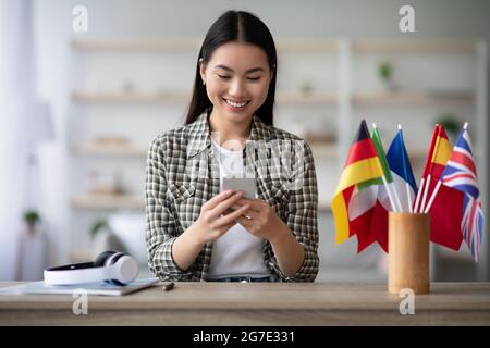 Cheerful asian young woman using cellphone, having English class Stock Photo
