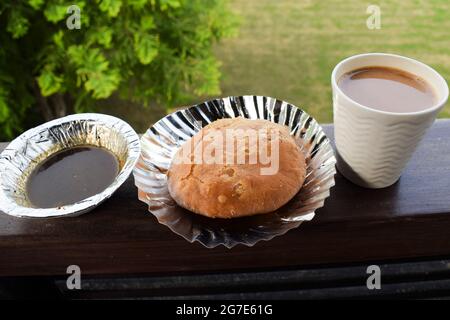 Indian breakfast Mung dal kachori snack item served with khajoor chutney and cup of tea.. Outdoors nature background on table balcony. Indian breakfas Stock Photo