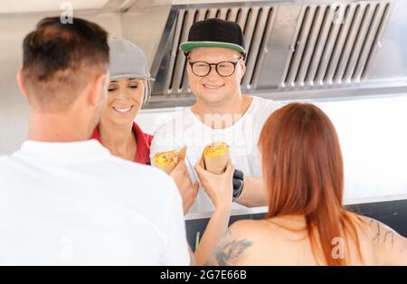 Chefs giving Burritos to customers of food truck waiting in line Stock Photo