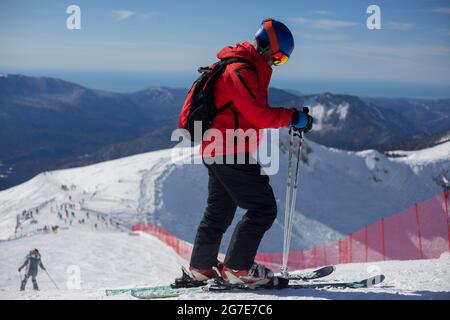 A skier rides on a snowy slope. Active rest in the winter. The athlete is preparing for the descent. Mountain ski resort. Outdoor activities on a wint