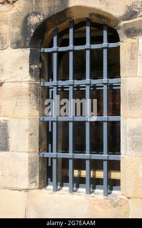 Close up of metal grille over window with stonework frame on a building in the main courtyard inside Lancaster Castle, Lancaster, Lancashire, Stock Photo