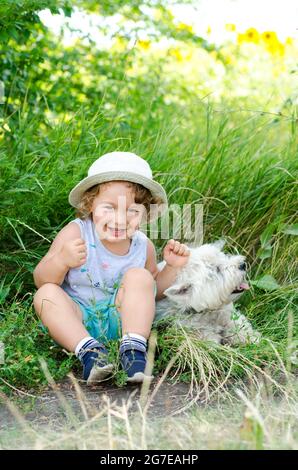 little boy and dog sitting in the grass Stock Photo