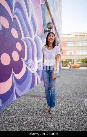 Young Asian Woman in 1960s Apparel Standing in Front of 1960s Style Mural Stock Photo