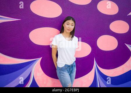 Young Asian Woman in 1960s Apparel Standing in Front of 1960s Style Mural Stock Photo