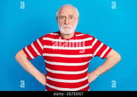 Portrait of attractive serious worried grey-haired man hands on hips isolated over bright blue color background Stock Photo