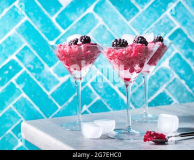 Mixed berry granita in a cocktail glass against a blue background Stock Photo