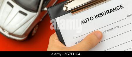 Car insurance form in hand. Desktop with car toy on background. Banner Stock Photo