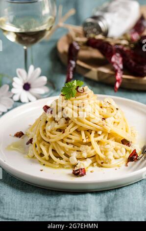 Spaghetti with salted codfish and chilli pepper, on a white ceramic plate Stock Photo