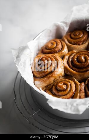 Cinnamon buns in a round pan with parchment paper. Stock Photo