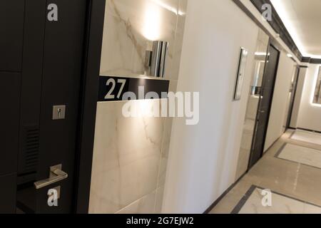 Hotel corridor with apartment number. Closed doors in the hallway. Hospitality business Stock Photo