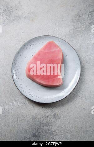 Fresh tuna steak on gray plate, gray background. Stock Photo