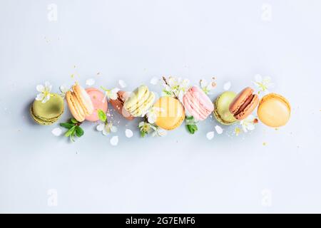 Vintage pastel colored French macaroons or macarons in motion falling on light blue background, pastel colors, vintage card, top view Stock Photo