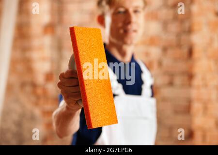 Bricklayer with tool at a construction site, focus is on the tool! Stock Photo