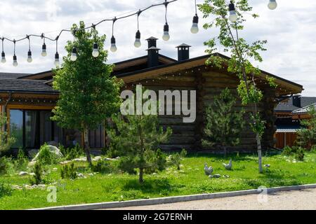 Beautiful wooden house with garlands on the background of landscape design Stock Photo
