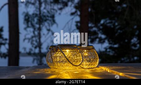 Portable garden lights on a wooden table outdoors in Finnish summer twilight Stock Photo