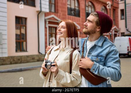 Tourism and technology. Happy young couple taking photo of old town. Traveling by Europe, walk in city, architectural historical building in the backg Stock Photo