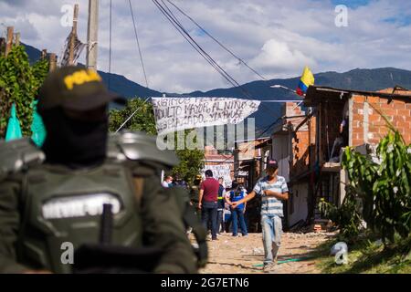 A Colombia's riot police officer (ESMAD) stands near the neighborhood amid a dangerous construction area, Colombia's child services (ICBF) and riot police (ESMAD) evict families that live in a low income neighborhood indangered to collapse due terrain in Itagui, Antioquia - Colombia. July 12, 2021 Stock Photo