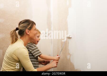 Family - mother with son - painting the wall of their new home or apartment, apparently they just moved in Stock Photo