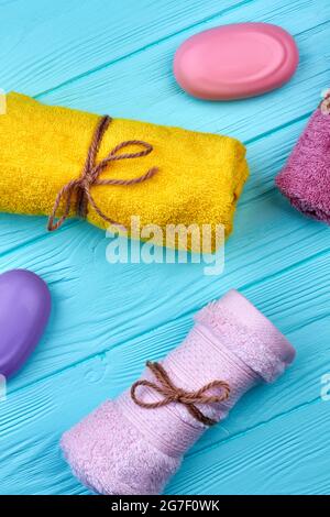 Colored terry towels and soap pieces on blue wood. Stock Photo